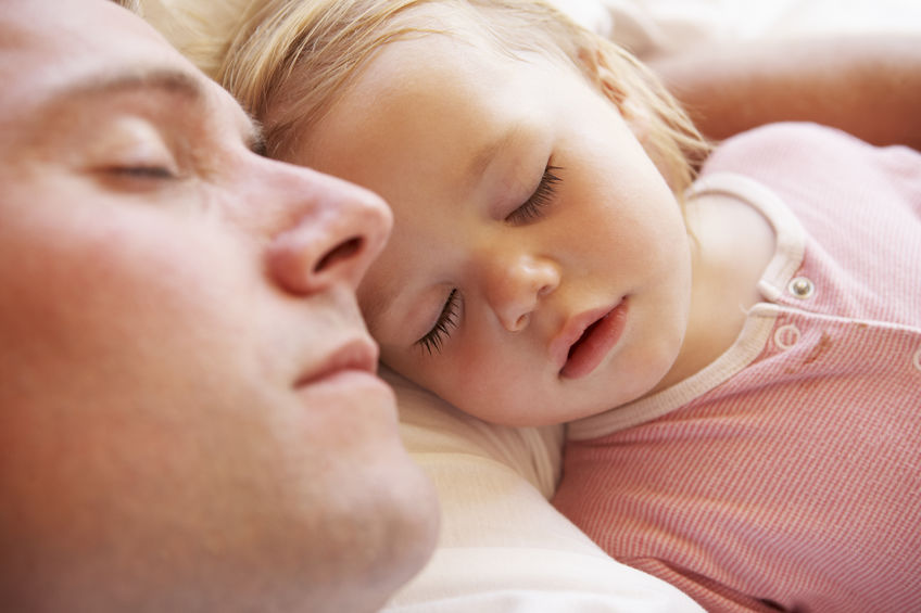 photo of father and baby daughter sleeping in bed